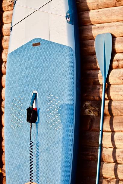 istock Paddleboard and surf board with paddle on brown wooden wall background close up 1325264899