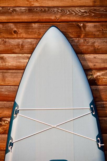 istock Paddleboard and surf board with paddle on brown wooden wall background close up 1325265057