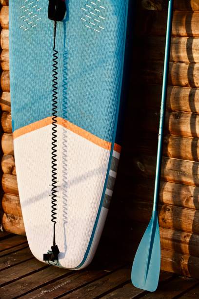 istock Paddleboard and surf board with paddle on brown wooden wall background close up 1325265209