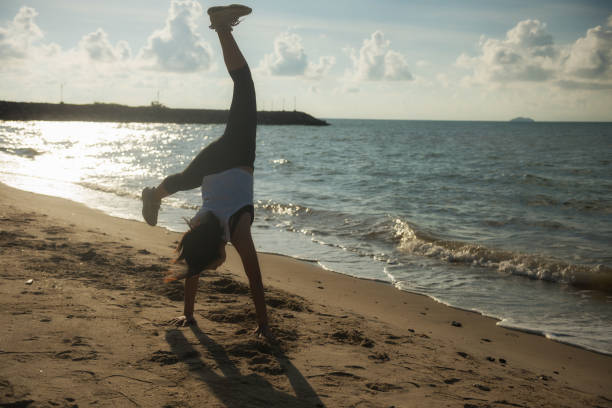 istock Young woman somersault on beach at sunrise 1325266898