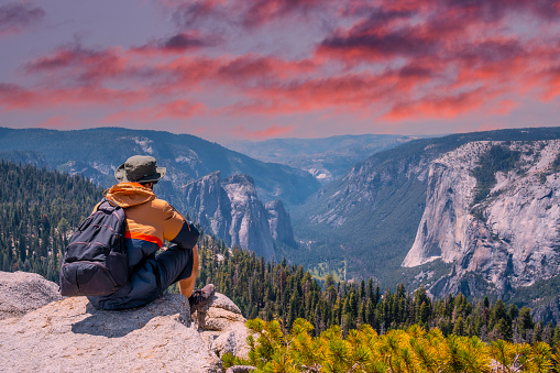 Un joven alado sentado Taft punto mirando el Parque Nacional de Yosemite y El Capitán en la puesta de sol. Estados Unidos photo