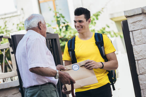 istock Young male volunteer delivering shopping to senior man. 1325267708
