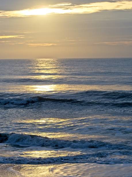 Morning sunrise across the Atlantic at Satellite Beach, Florida. A tranquil summer sunrise and glistening water as ocean swells move in to the coast.