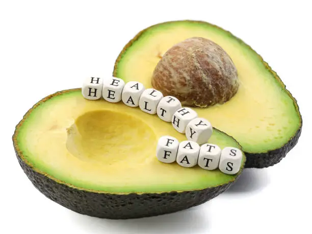 Photo of halved avocado with text healthy fats from cubes with letters isolated on white background