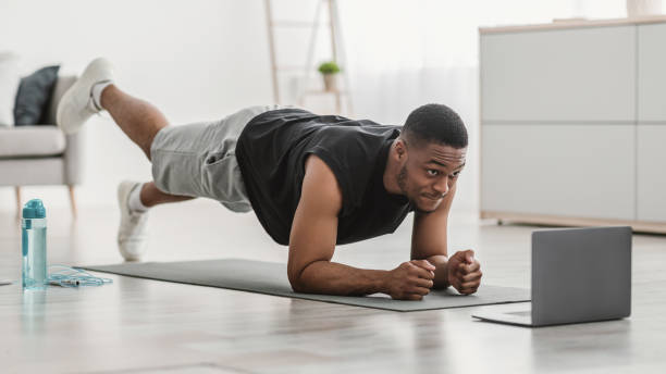 istock Man At Laptop Standing In Plank Doing Leg Raise Indoor 1325273624