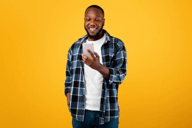 istock Joyful African American Male Holding Cellphone Using Mobile App, Studio 1325273671