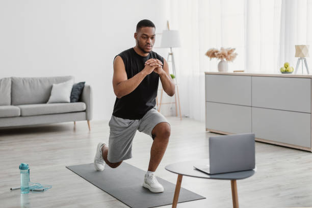 istock African Man Training At Laptop Doing Forward Lunge At Home 1325274305