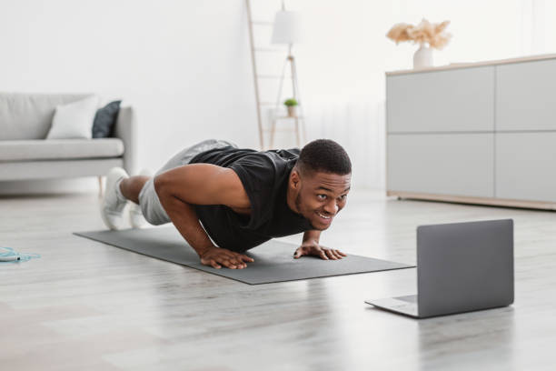 istock Athletic African Guy Exercising At Laptop Doing Push-Ups At Home 1325274385