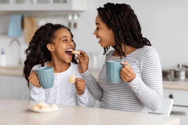 istock Happy black mom feeding her kid with cookies 1325274494