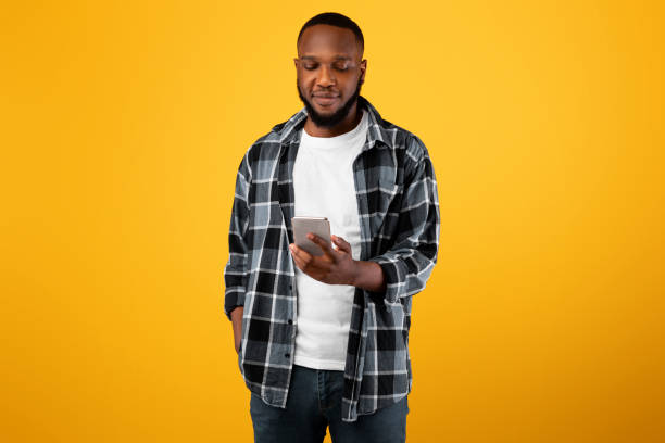 istock African American Millennial Guy Using Smartphone Texting Standing In Studio 1325274557