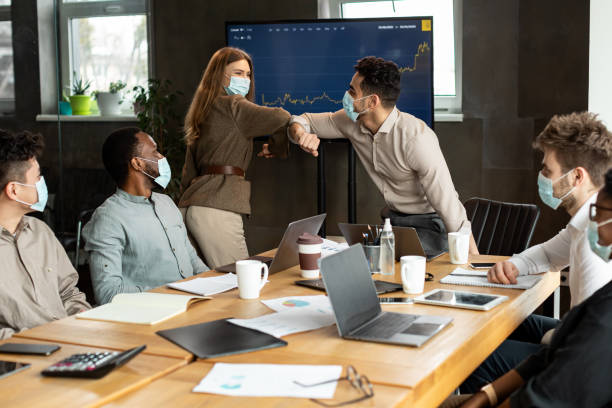 istock Diverse workers wearing face masks greeting and bumping elbows 1325274749