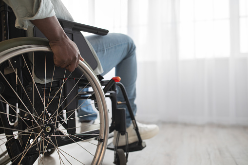 New rules of life after injury or disease, depression and self-isolation after incident. Millennial african american man disabled in wheelchair on window background in clinic or room interior, cropped
