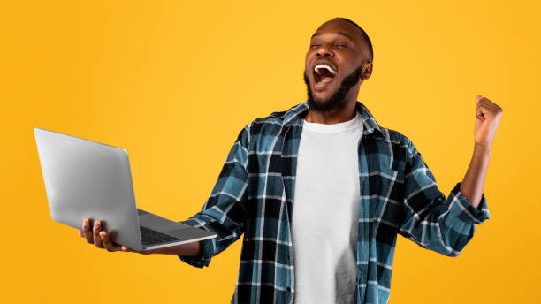 istock Excited Black Guy Holding Laptop And Shouting Gesturing Yes, Studio 1325274908