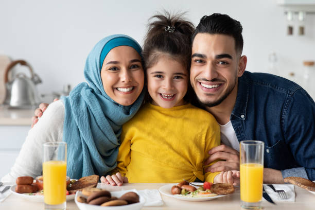 padres islámicos felices con hija pequeña posando en la cocina, almorzando juntos - domestic kitchen father eating child fotografías e imágenes de stock