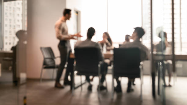 Colleagues having meeting in boardroom, businessman giving speech, blurred photo Business Presentation, Blurred Background. Businessman Giving Speech During Seminar With Coworkers In Office, Standing At Desk In Boardroom, Diverse People Sitting At Table And Listening To Speaker meeting stock pictures, royalty-free photos & images