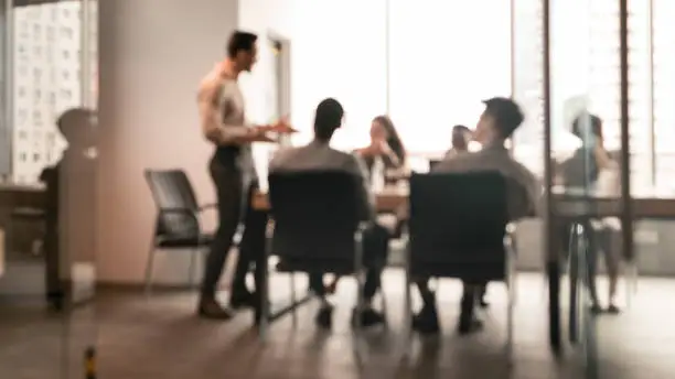 Photo of Colleagues having meeting in boardroom, businessman giving speech, blurred photo