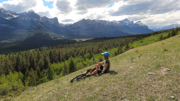 istock Female mountain biker relaxes on grassy mountain ridge 1325277030