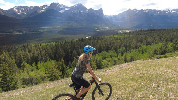 istock Female mountain biker rides along grassy mountain ridge 1325277106