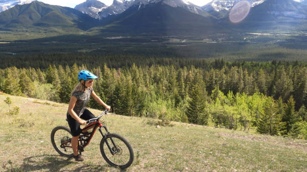 istock Female mountain biker rides along grassy mountain ridge 1325277116