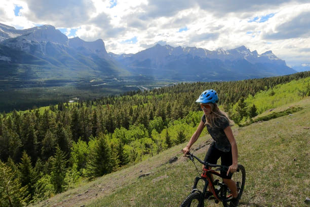 istock Female mountain biker rides along grassy mountain ridge 1325277144