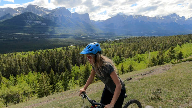 istock Female mountain biker rides along grassy mountain ridge 1325277169
