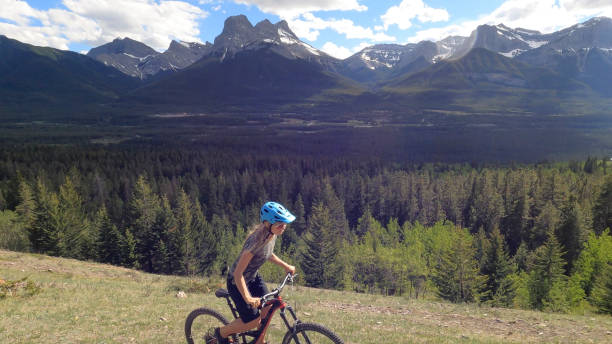 istock Female mountain biker rides along grassy mountain ridge 1325277192