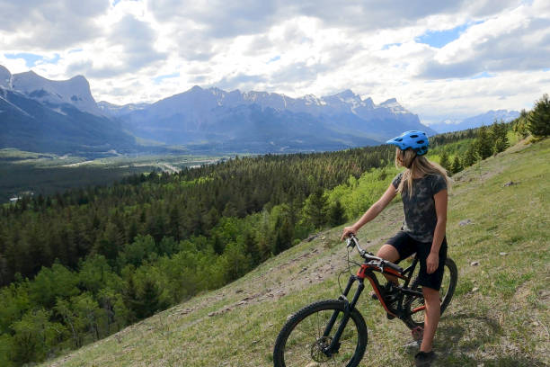 istock Female mountain biker relaxes on grassy mountain ridge 1325277204