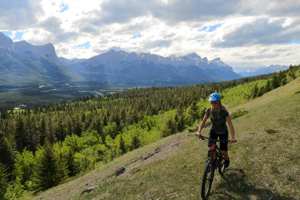 istock Female mountain biker rides along grassy mountain ridge 1325277229