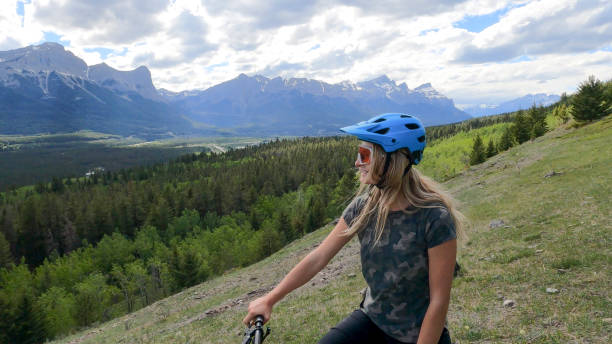 istock Female mountain biker relaxes on grassy mountain ridge 1325277231