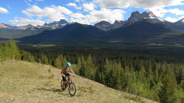 istock Female mountain biker rides along grassy mountain ridge 1325277245