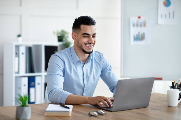istock Handsome young Arab businessman working with laptop computer at his desk in office 1325277343