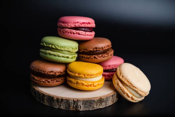 macarons cookie dessert dalla francia in una pila su tavola di legno e sfondo nero - amaretto foto e immagini stock