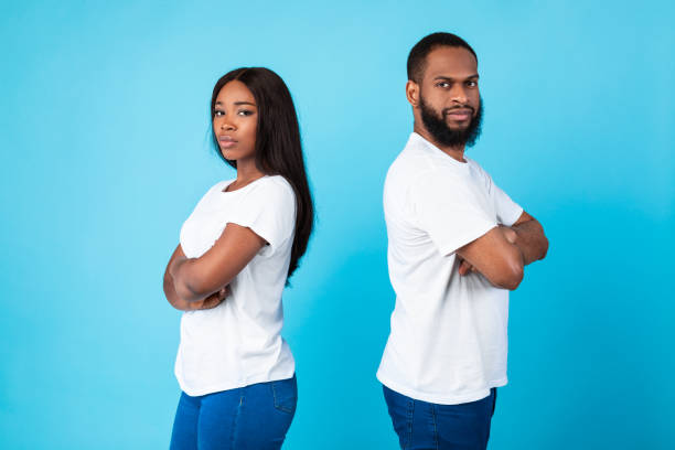 istock Afro couple standing back to back, blue studio background 1325278907