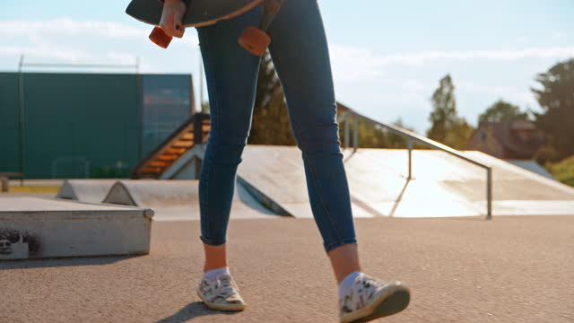 Teenage girl carrying skateboard in skate park