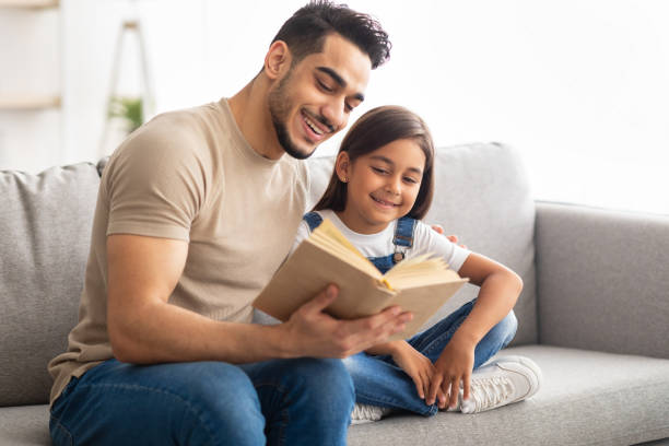 istock Father and daughter reading book spending time together at home 1325279712