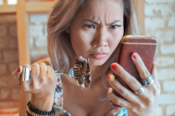 istock Woman upsetting while eating cake and checking her mobile phone 1325280684