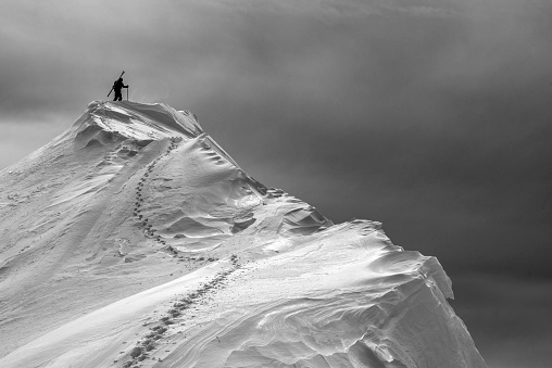 He trods through deep snow, leaving a track behind on ridge of Canadian Rockies