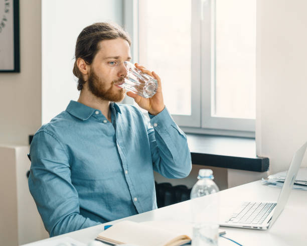 istock Young man drinking pure mineral water while working on laptop 1325281147