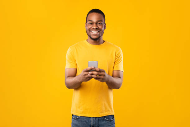 istock Happy African American Guy Using Phone Standing Over Yellow Background 1325281978
