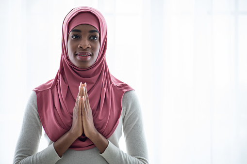 Portrait Of Black Islamic Lady In Hijab Praying With Clasped Hands Near Window At Home, Young Religious African Muslim Female Woman In Headscarf Feeling Blessed, Closeup Shot With Copy Space