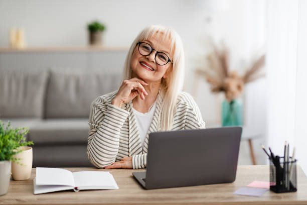 istock Mature woman sitting at desk with computer and posing 1325282155