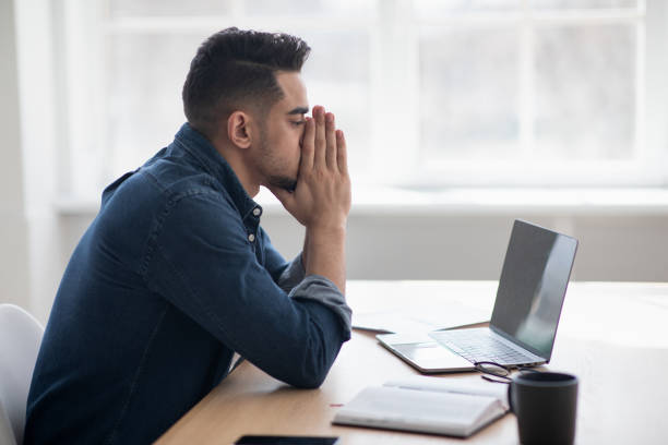 istock Exhausted arab man sitting in front of laptop, office interior 1325282328