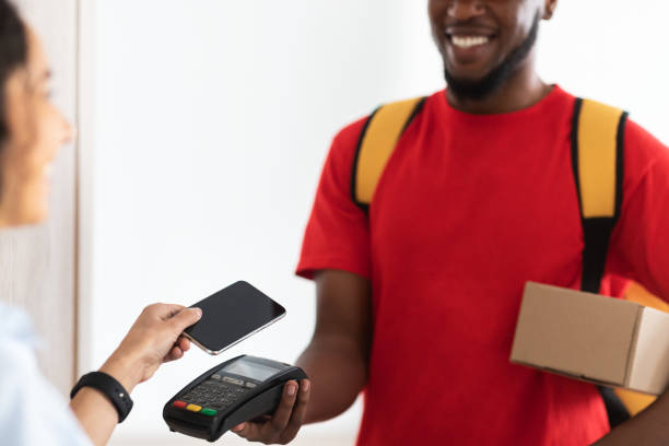 istock Black man holding POS terminal client paying with smart phone 1325283175