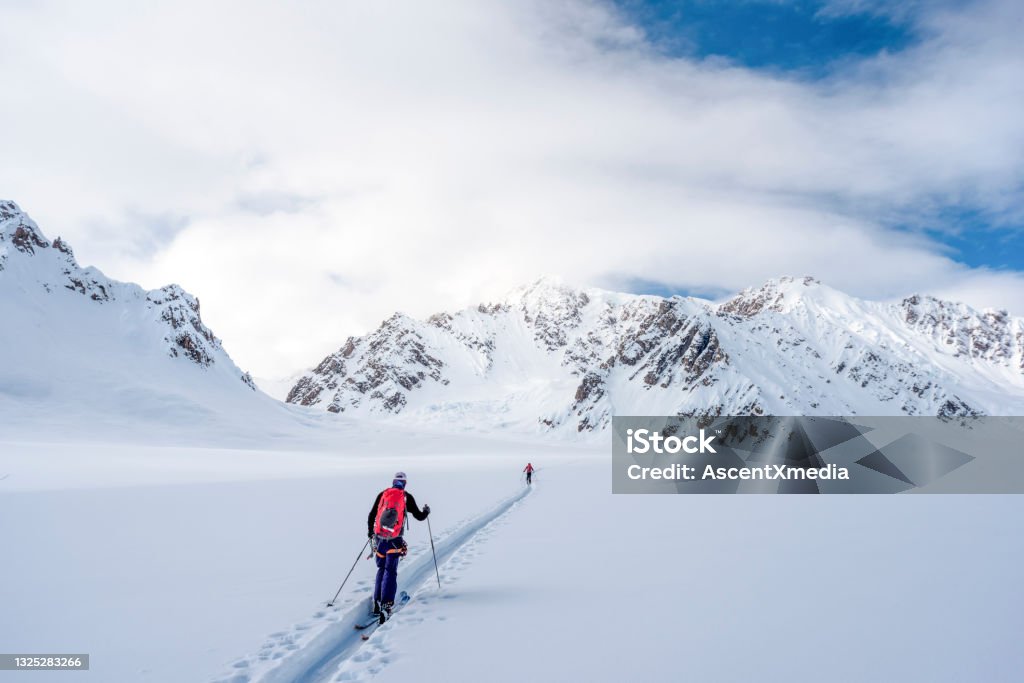 Backcountry skiers climb snowy Canadian Rockies They trod through deep snow, leaving a track behind them Skiing Stock Photo