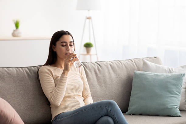 mujer disfrutar de buen hábito beber aguamarina mineral por la mañana cuidar de la piel, el cuerpo, la salud y la belleza - young women sitting simple living eastern europe fotografías e imágenes de stock