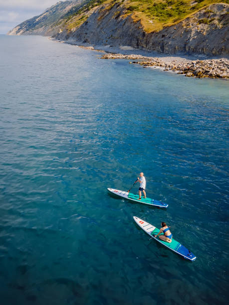 13. juni 2021. anapa, russland. luftaufnahme des paares auf stand up paddle board am blauen meer. menschen, die auf red paddle sup board im ozean reisen. - editorial women paddleboard surfboard stock-fotos und bilder