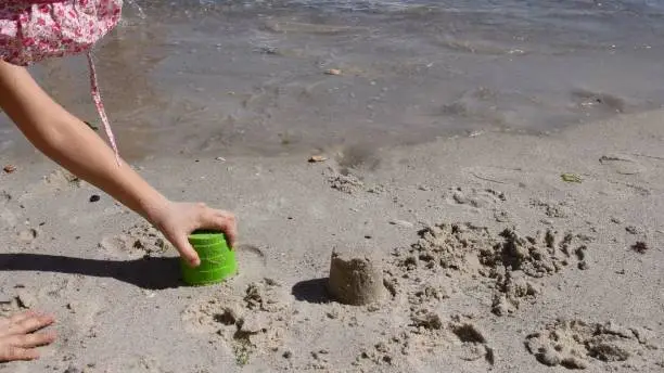 Photo of Child hand makes sandcastle with sand mold tool