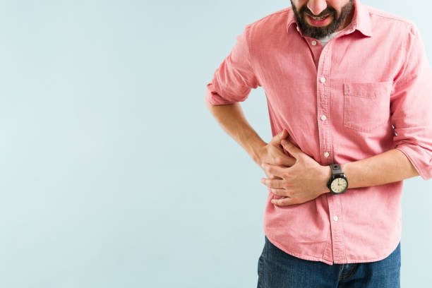 Attractive man rubbing the side of his stomach Close up of a stressed man in his 30s suffering from a gallbladder sickness. Latin man in a lot of pain due to gallstones next to copy space gall bladder stock pictures, royalty-free photos & images