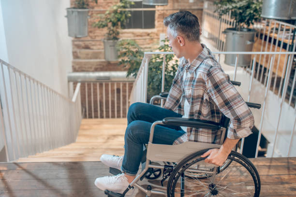 istock Man on wheelchair near steps down indoors 1325290243
