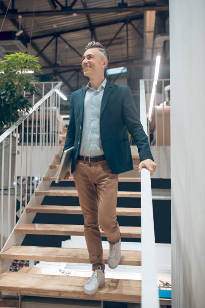 istock Man with laptop standing on stairs in office 1325290257